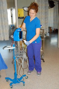 Lauren Tennant, RN, wipes down a Dinamap vital signs patient monitor. During Acute Medicine's pilot, nurses were assingned their own Dinamap at the start of each shift, and they were responsible for cleaning between patients.