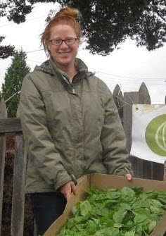 Garden coordinator Emily Neufeld holding a box of fresh spinach.