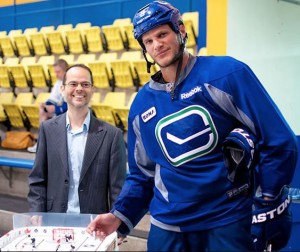 Rob Tarzwell (left) with Vancouver Canucks defenceman Kevin Bieksa who is signing the table hockey tournament prize.
