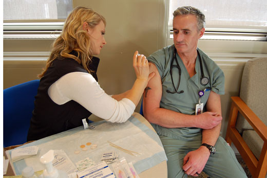 PNI Sylvia Szolomicki gives Brent Haley, VGH RN, his annual flu shot.
