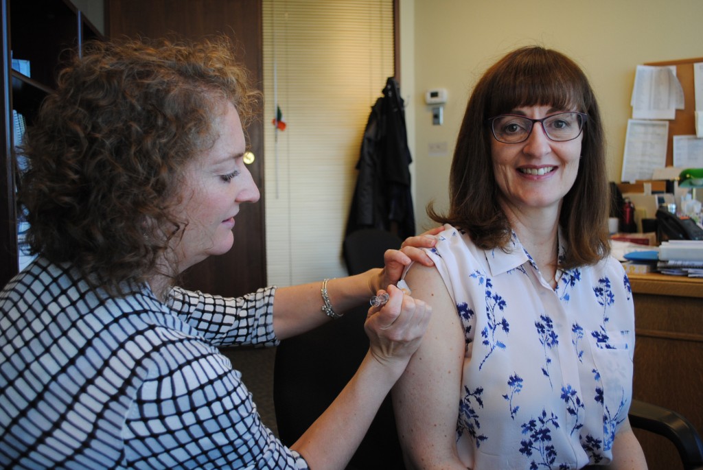 Marion Guenther vaccinates Dr. Patricia Daly for flu.